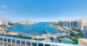 Un paysage urbain côtier avec un port de plaisance, des immeubles de grande hauteur et un ciel bleu dégagé.
