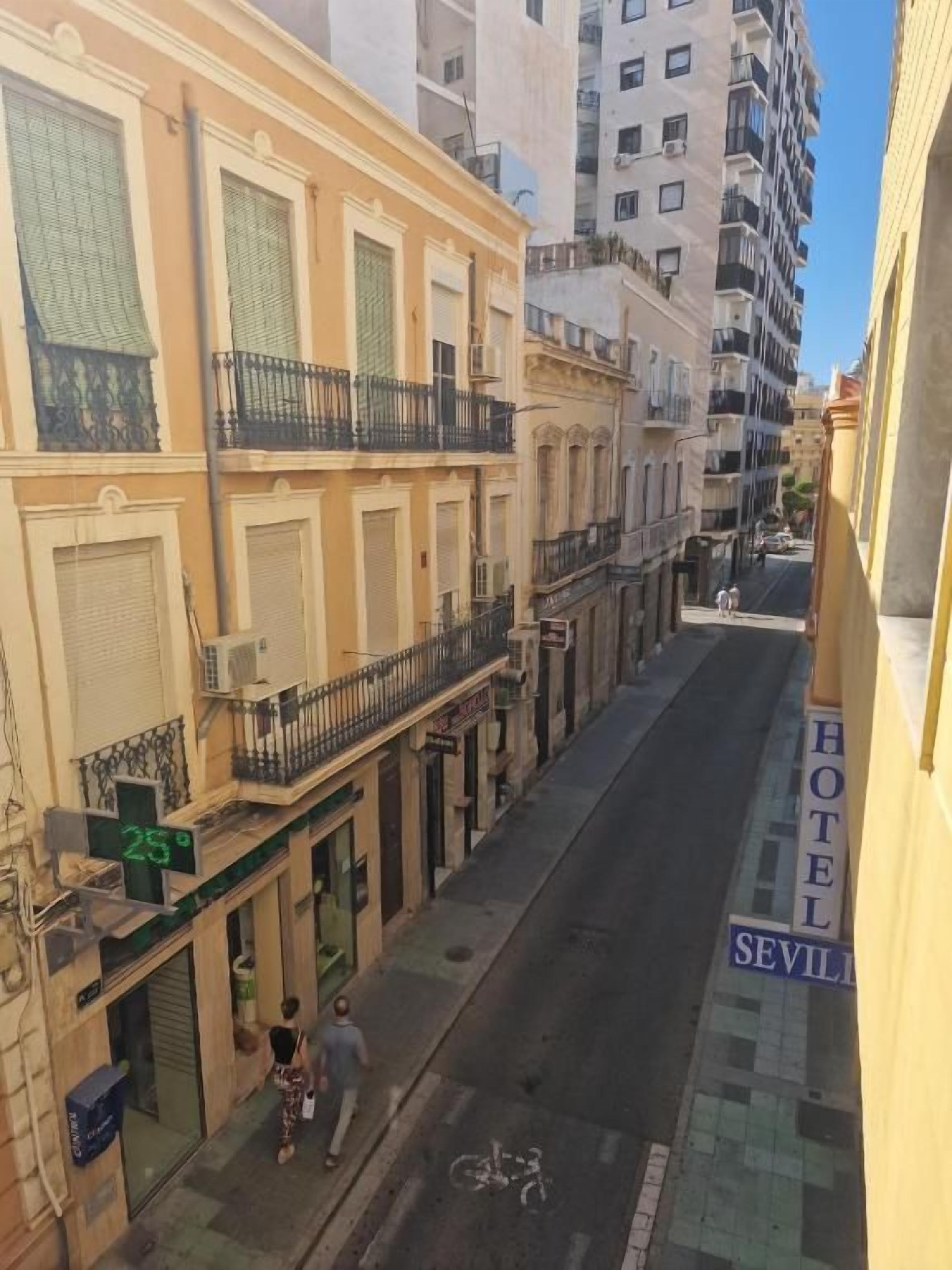 Un carrer estret amb edificis a ambdós costats, un senyal de hotel visible i una bicicleta a la vorera.