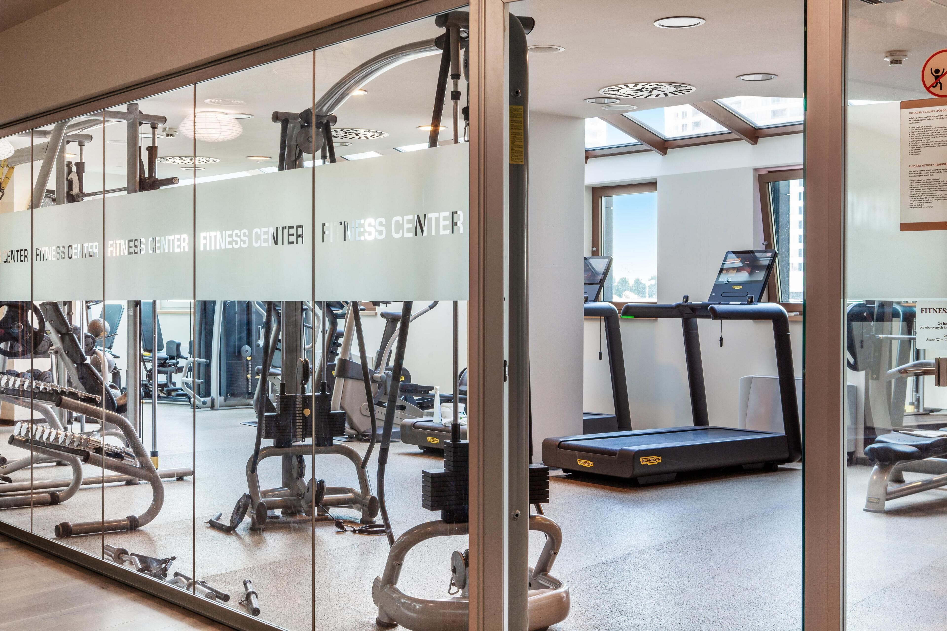 Un gimnasio con paredes de espejo, equipamiento de ejercicio y una cinta de correr.