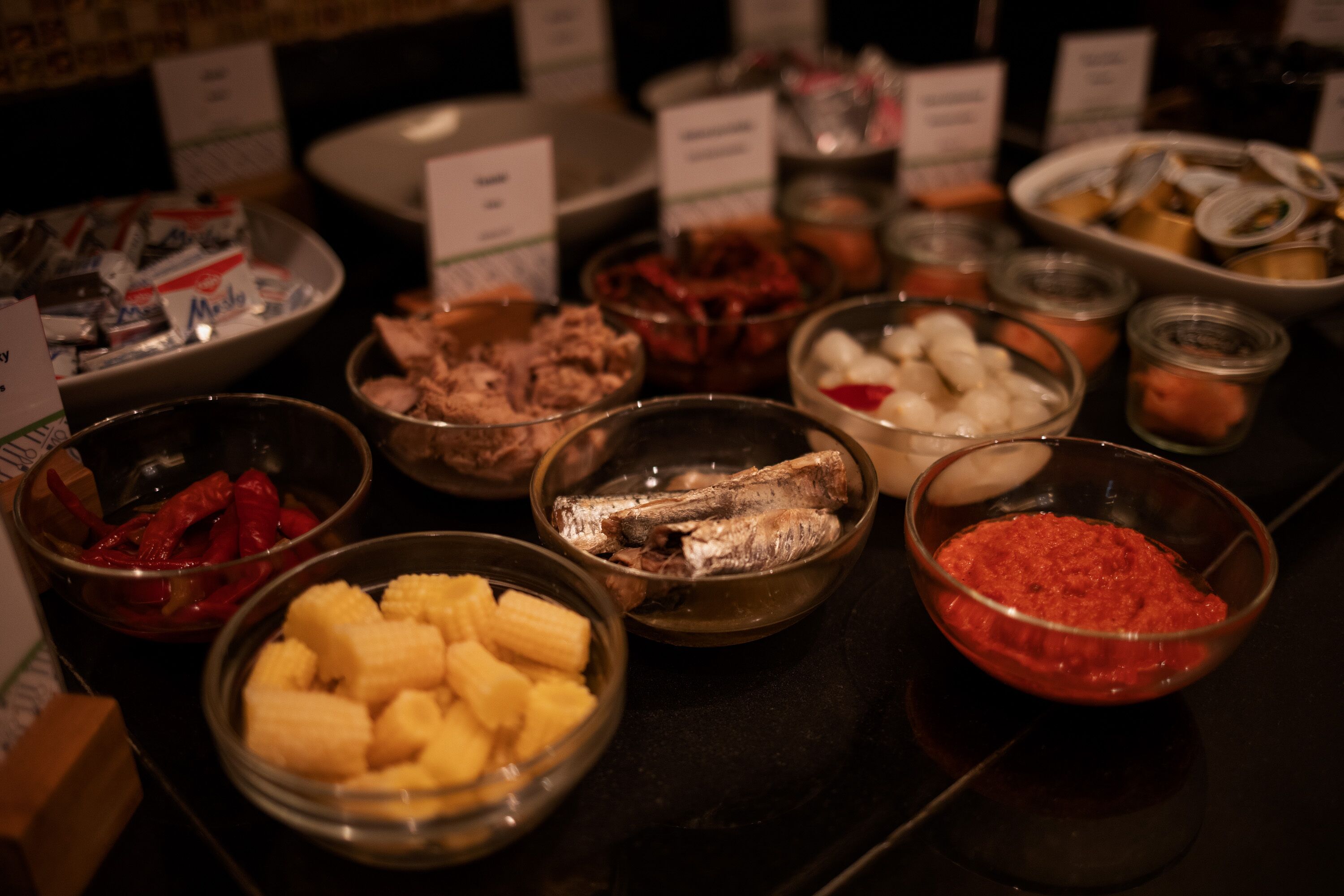 Ein Buffet mit verschiedenen Speisen, darunter Mais, Fisch und eine rote Soße.