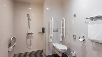 Un baño moderno con ducha, inodoro y barras de apoyo.