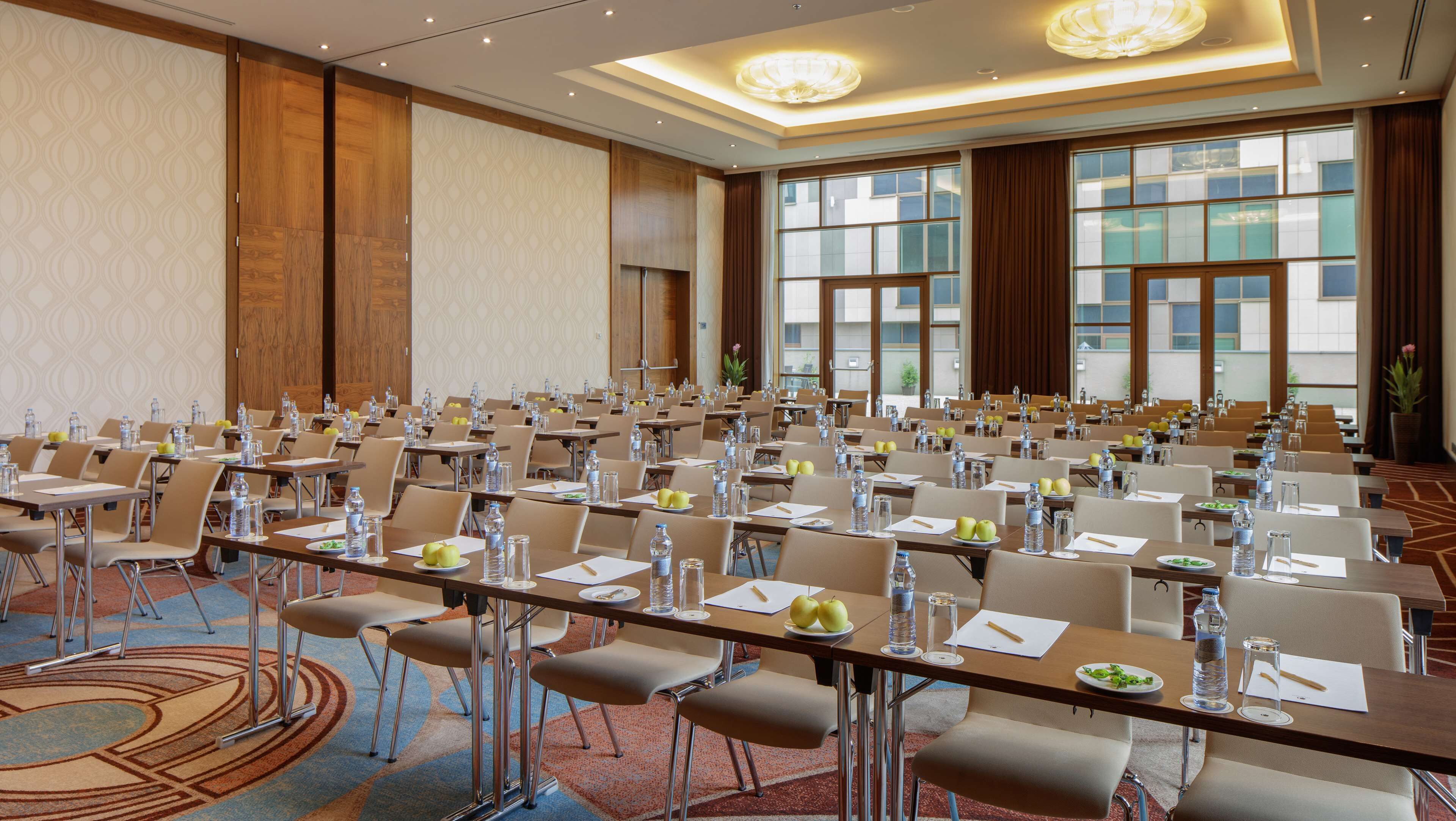A conference room with rows of tables, chairs, and water bottles, equipped with nameplates and pens.