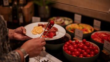 A buffet with various food items including a plate with cherry tomatoes, a bowl of sliced tomatoes, and a dish with scrambled eggs.