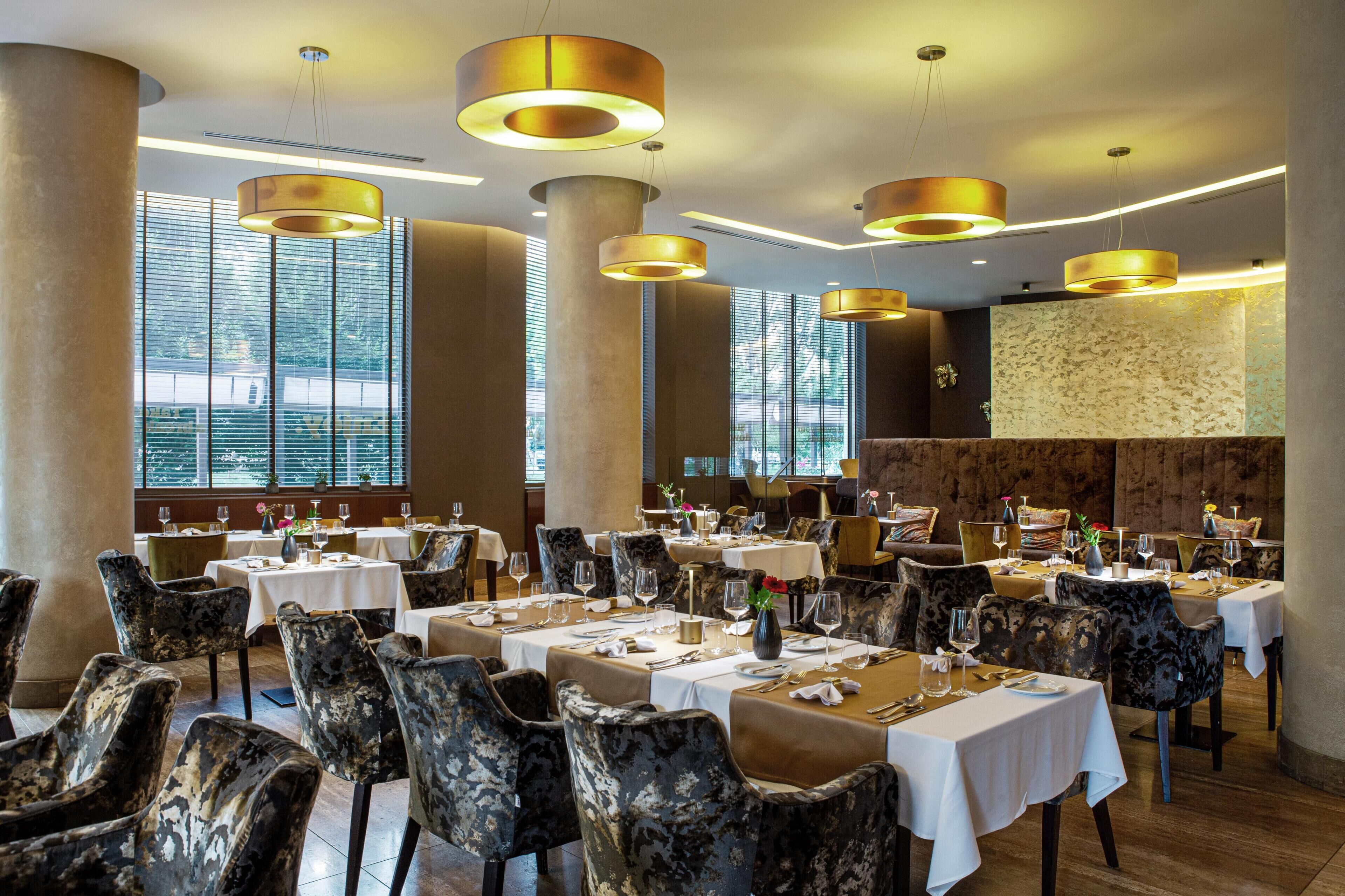 Un restaurante con varias mesas, sillas e iluminación colgante.