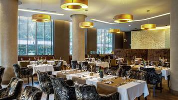 Un restaurante con varias mesas, sillas e iluminación colgante.