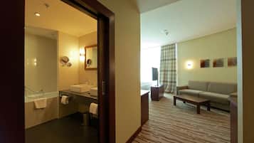 A hotel room with a bathroom, a sofa, a coffee table, and a zebra-patterned carpet.