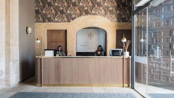 A reception desk with a wooden finish, a floral patterned wall behind it, and a glass door to the right.