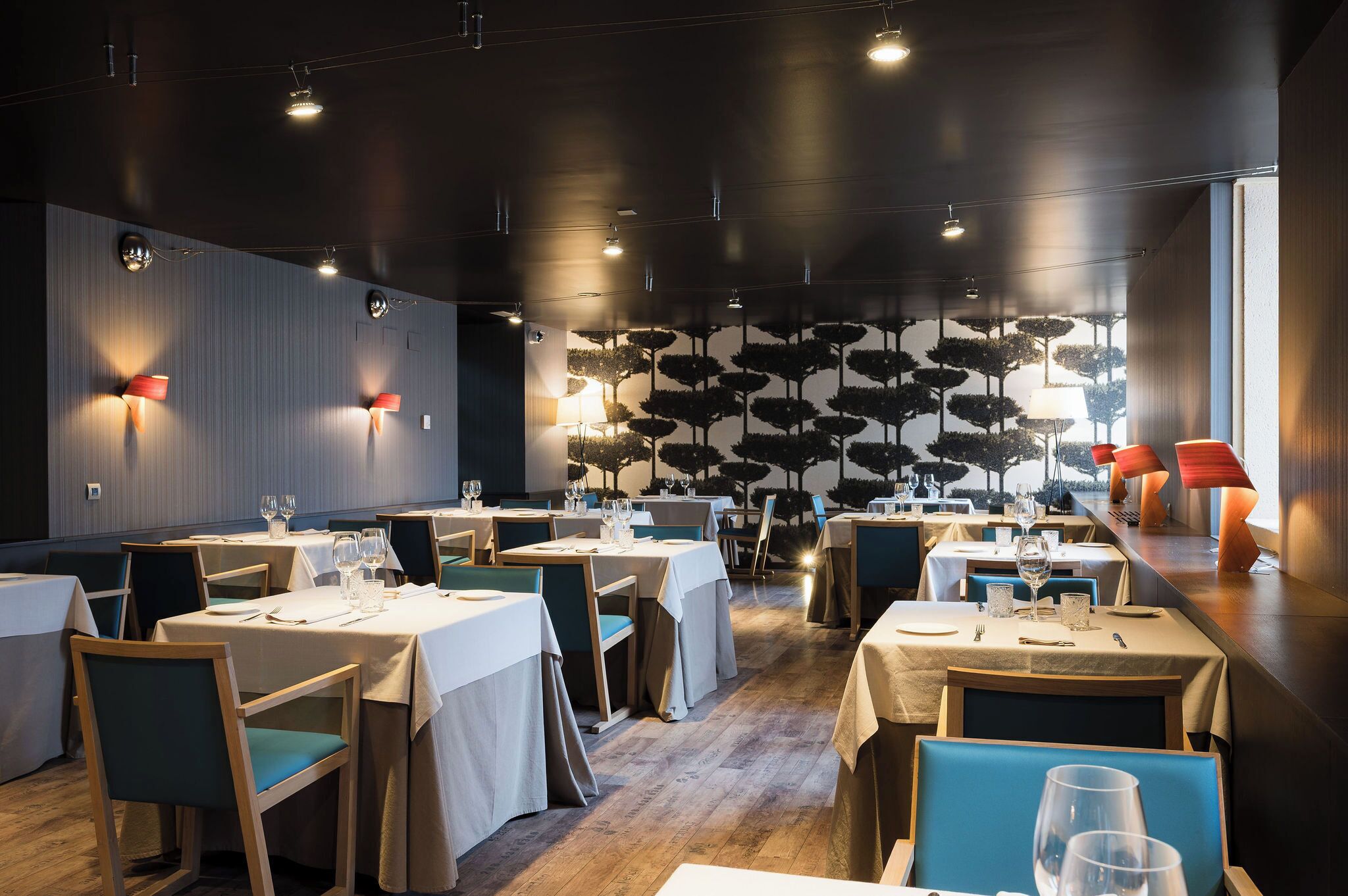 Un restaurante con varias mesas, sillas e iluminación en la pared.
