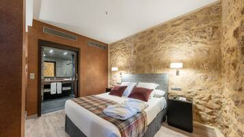 Una habitación de hotel moderna con una cama grande, un tocador integrado y una pared decorativa de piedra.