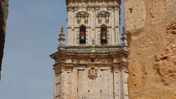 A historic bell tower with intricate architectural details, including a dome and multiple bells, viewed through an archway.