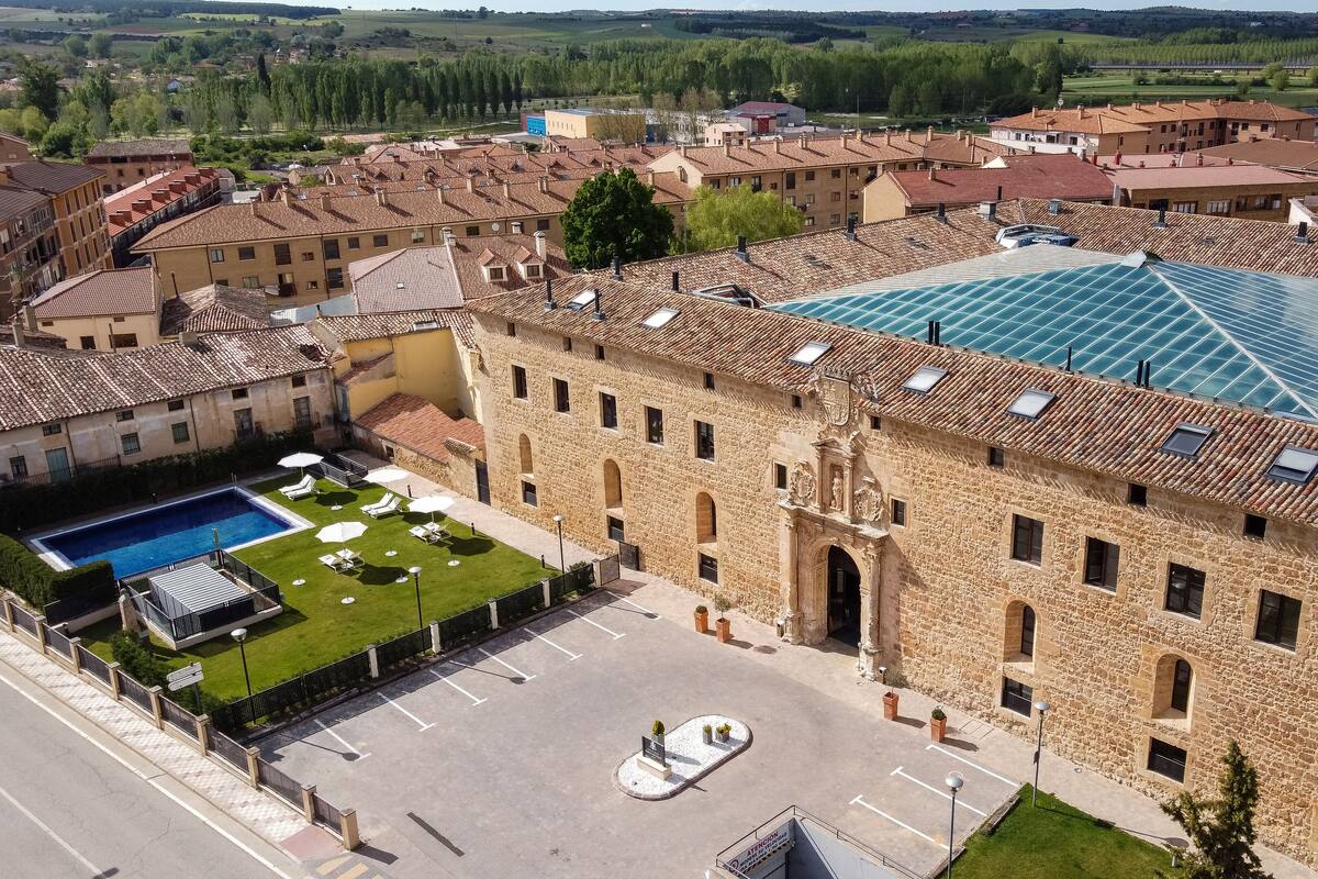 Un grand bâtiment en pierre doté d’une piscine, de nombreuses fenêtres et d’une cour intérieure.