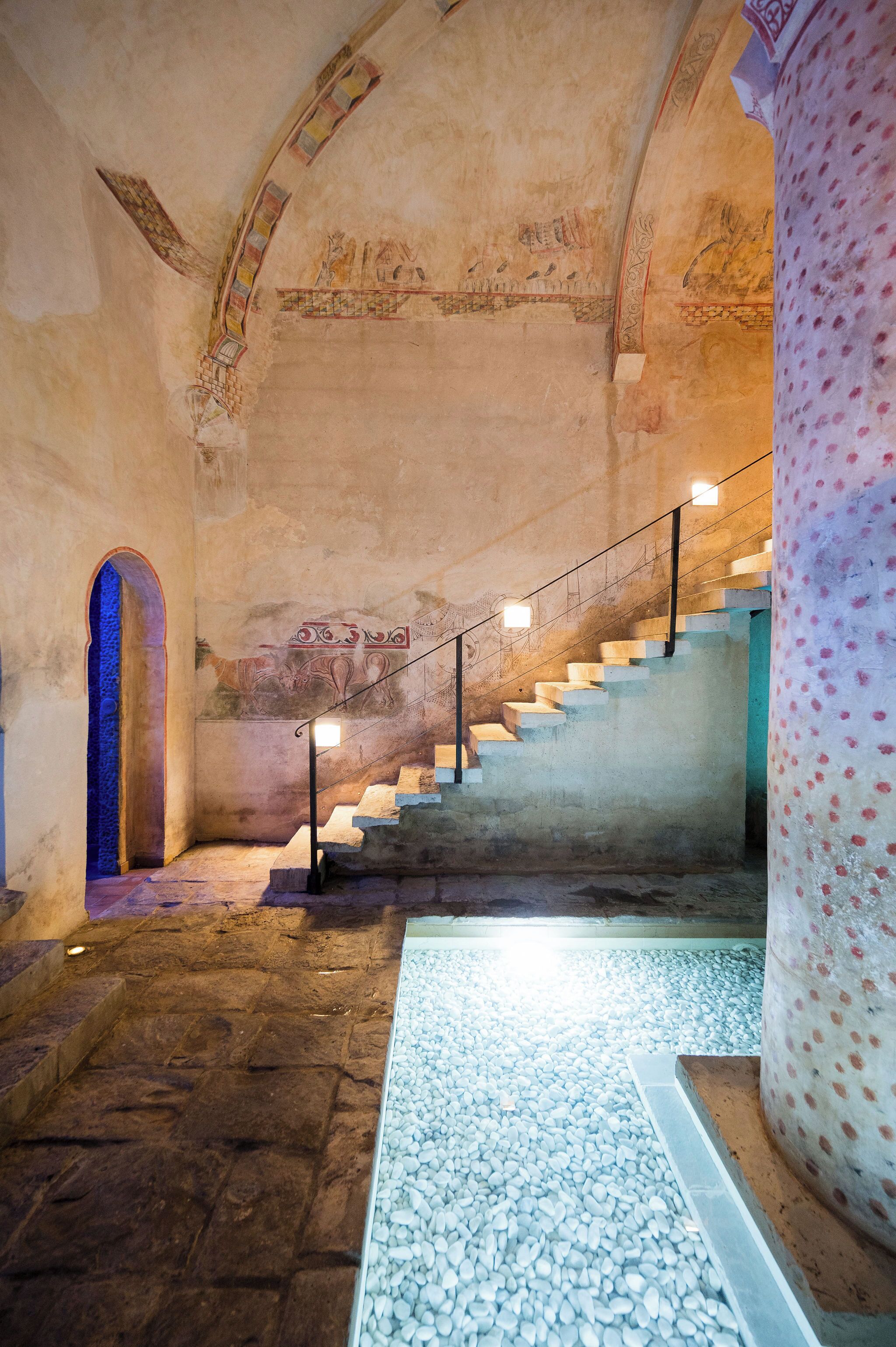 A staircase with stone steps and a metal railing, leading to an upper level.