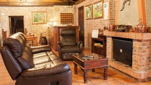 Una sala de estar acogedora con sofás de cuero, chimenea y pared de piedra.
