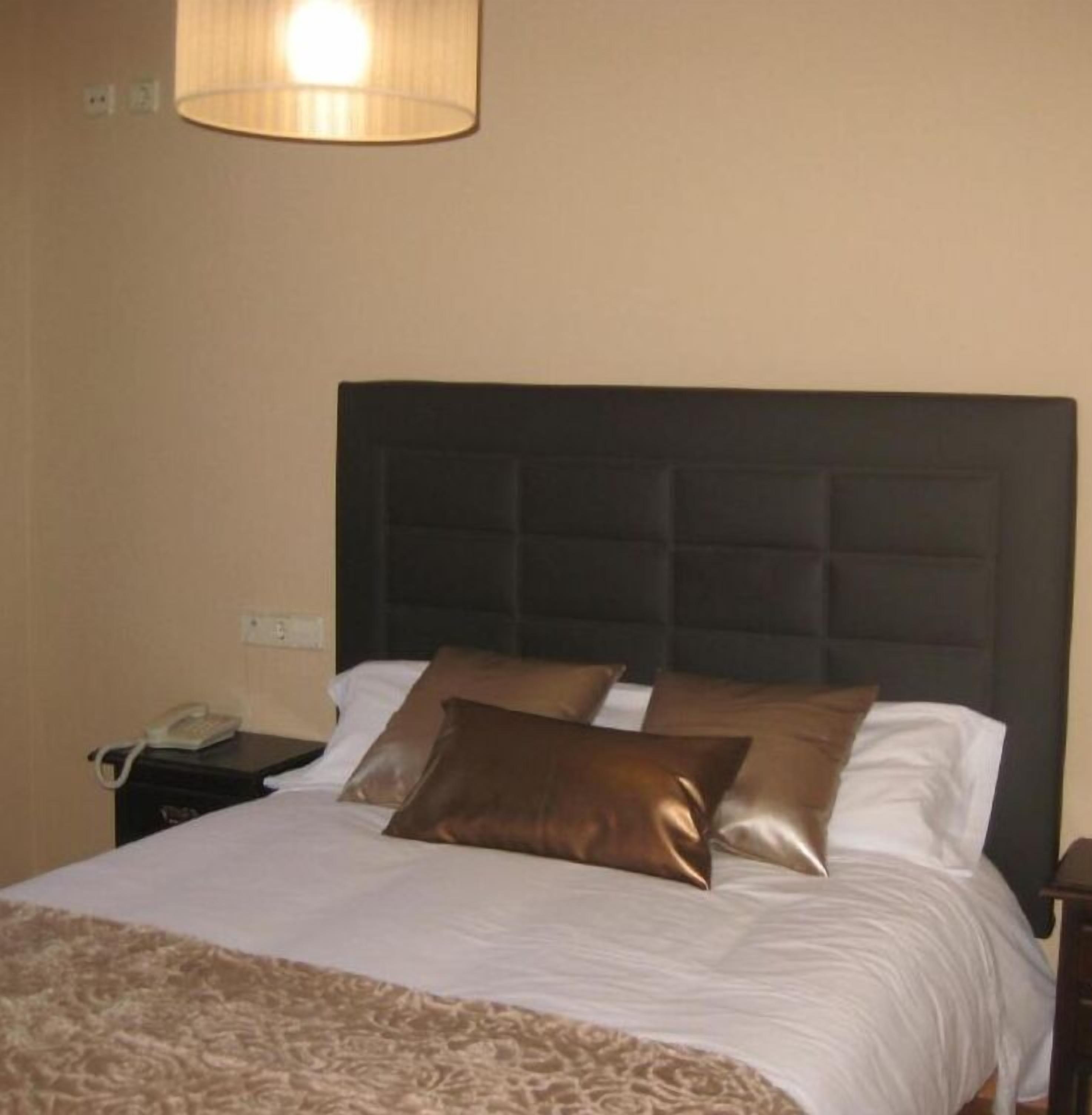 Una habitación de hotel con una cama, una mesita de noche, una lámpara y un teléfono.
