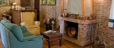 A cozy living room with a brick fireplace, a sofa, a chair, and a coffee table.