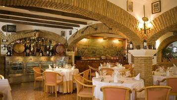 A restaurant with stone arches, wooden tables, and wine bottles.