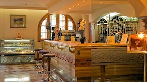 A bar area with a marble counter, stools, and a display case with food items.
