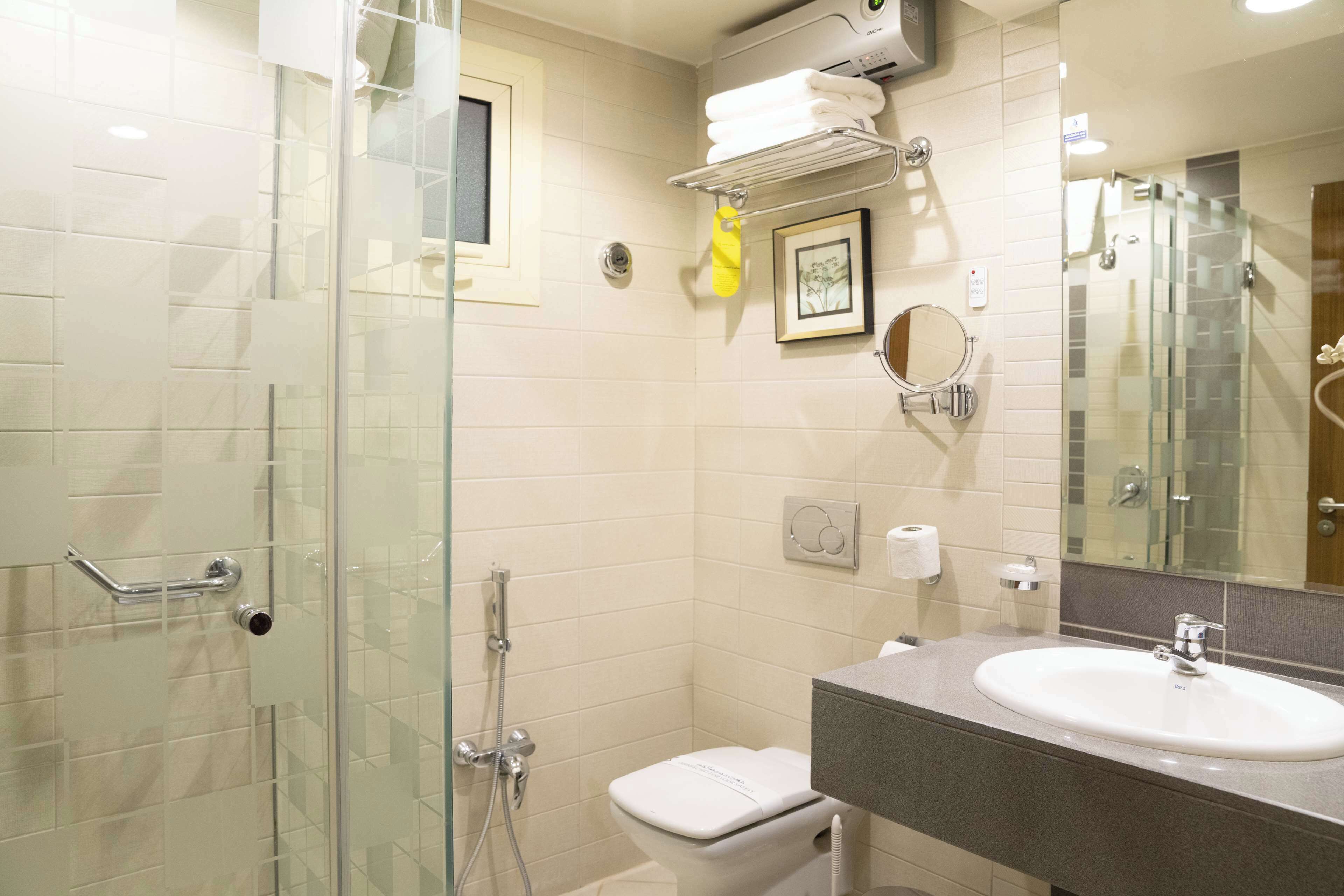 A modern bathroom with a glass-enclosed shower, a white toilet, a sink with a mirror, and a towel rack.