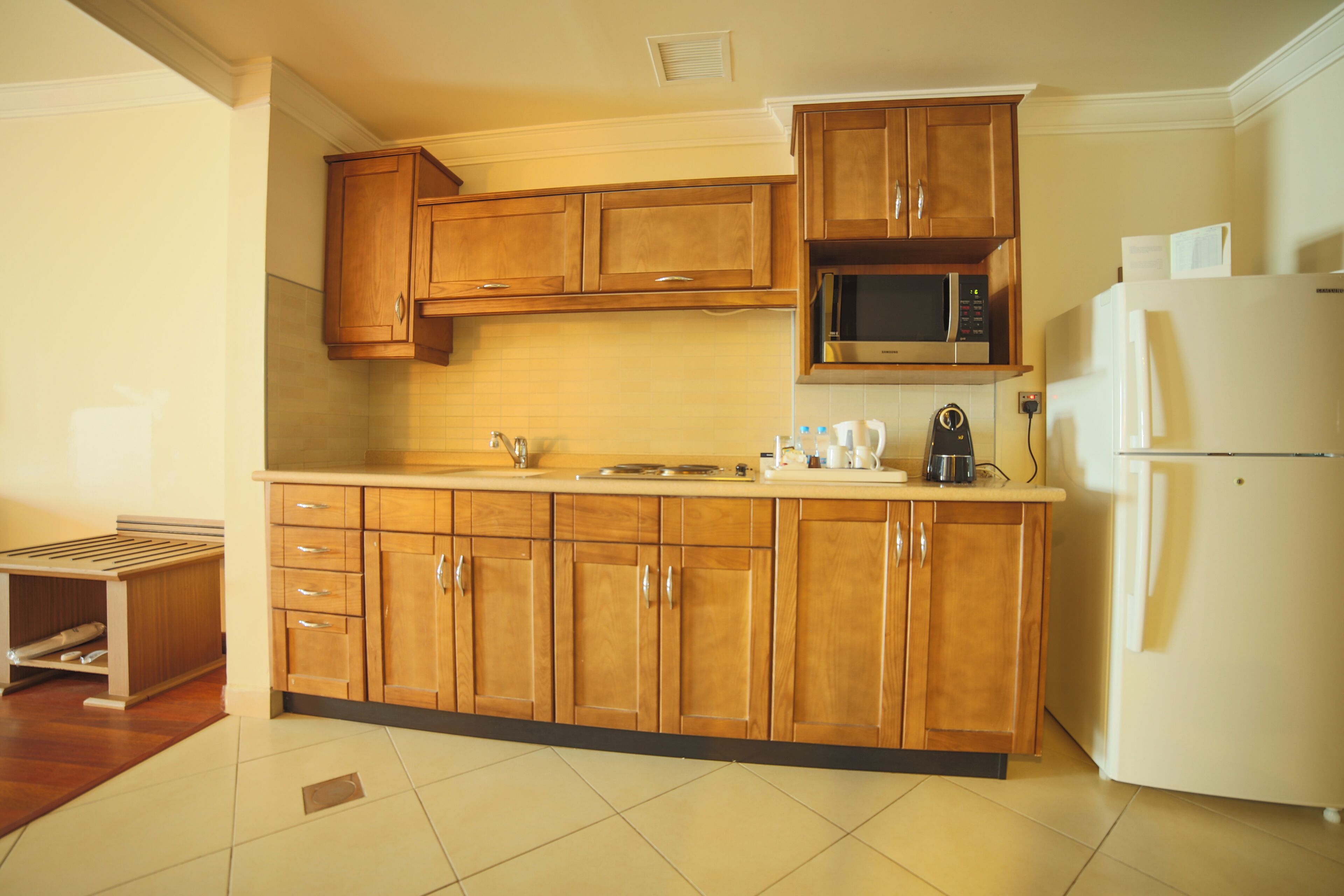 A kitchen with wooden cabinets, a microwave, a refrigerator, and a coffee maker.
