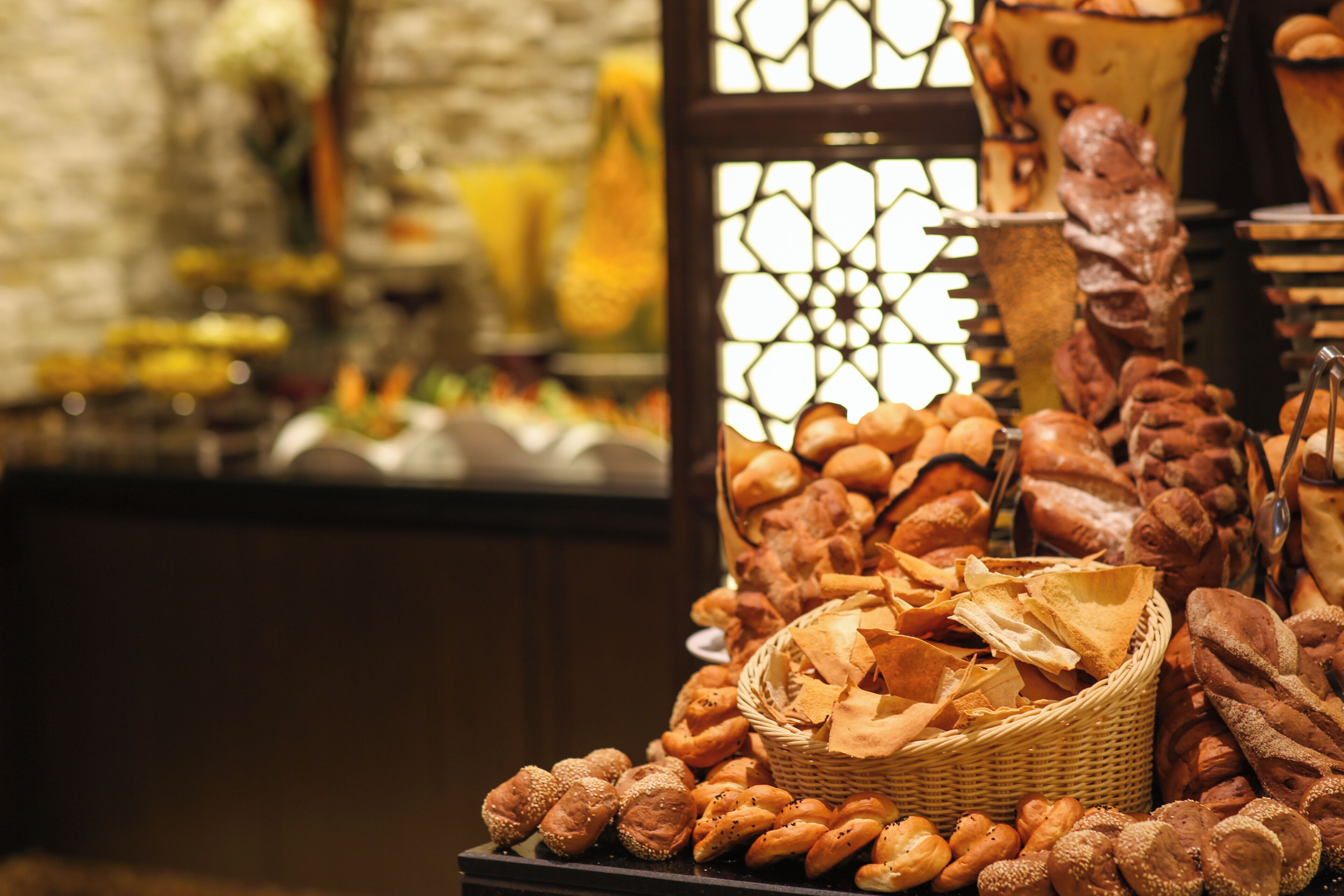 A variety of breads and pastries displayed on a table with a wicker basket.