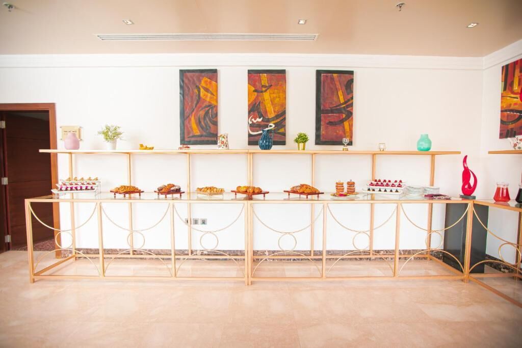 A reception area with a long table displaying various food items and decorative vases.