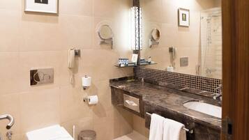 A modern bathroom with a marble sink, a toilet, a shower, and a mirror.