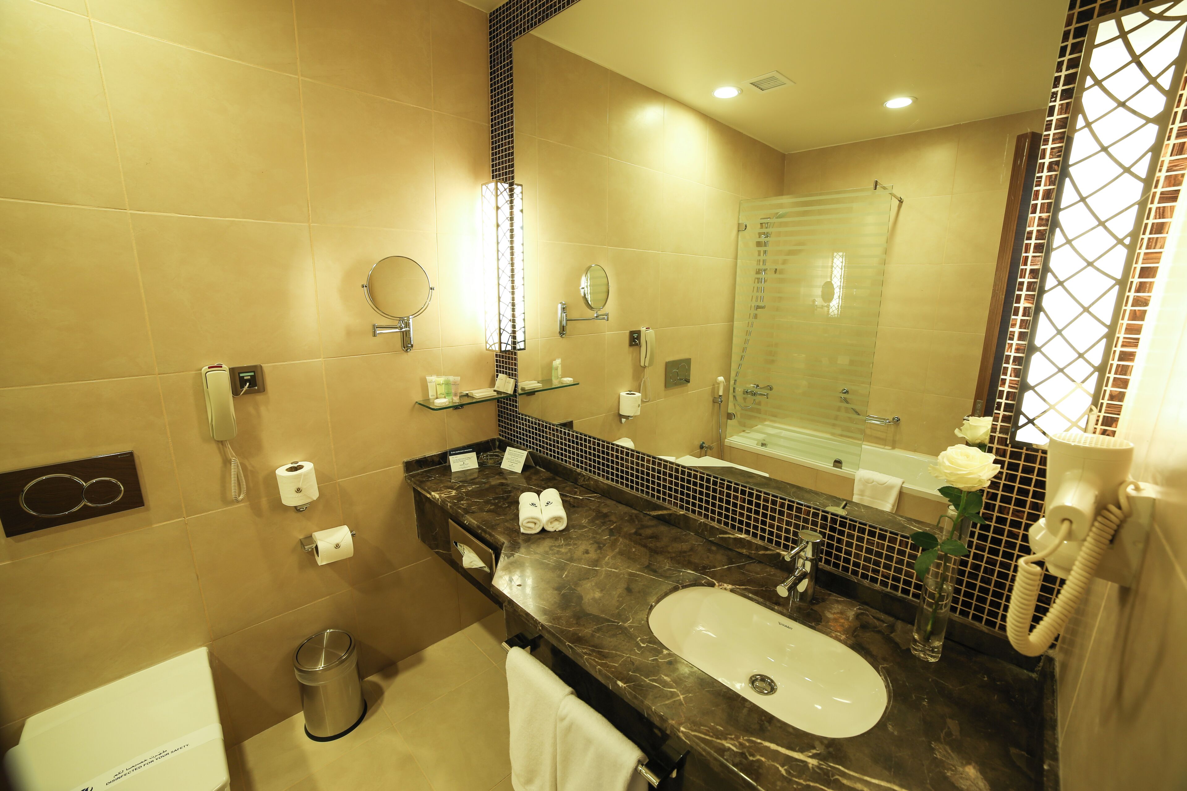 A modern bathroom with a marble sink, a glass shower enclosure, and a large mirror.