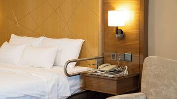 Ein Hotelzimmer mit Bett, Nachttisch, Lampe und einem Sessel.