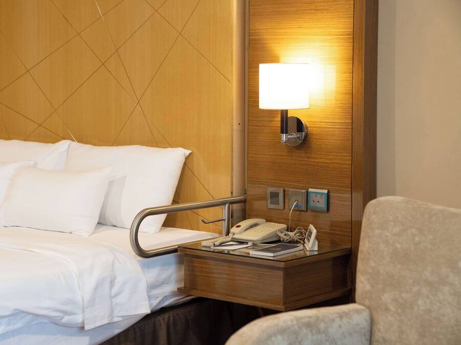 Ein Hotelzimmer mit Bett, Nachttisch, Lampe und einem Sessel.