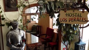 Ein Zimmer mit einer Statue eines Ritters aus dem Mittelalter, einem Schild mit der Aufschrift "HOSTAL LOS PERALES" und einem rustikalen Essbereich.