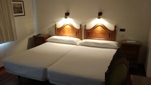 Ein Doppelbett mit Holz Kopfteil und Nachttischen, ein Sessel und ein kleiner Schreibtisch mit Lampe.