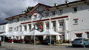 Ein Gebäude mit mehreren weißen Zelten davor, einem Schild mit der Aufschrift 'HOTEL' und mehreren parkenden Autos.