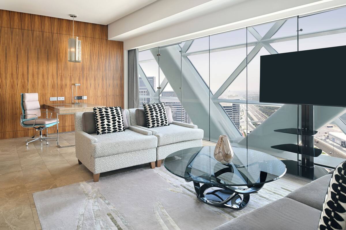 Ein modernes Wohnzimmer mit einem Glastisch, einer Couch, einem Sessel und einem Fernseher.