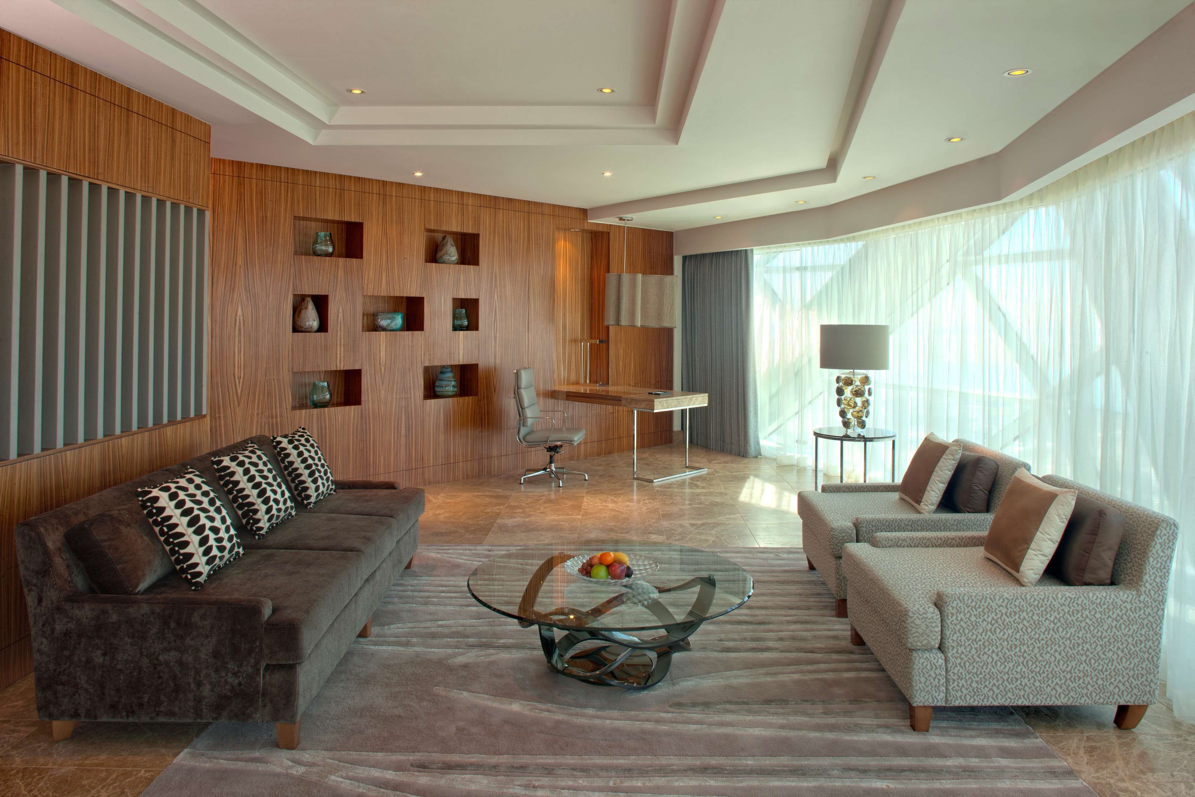 Ein modernes Wohnzimmer mit zwei Sofas, einem Glastisch und einem Essbereich mit Tisch und Stühlen.