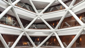 Un atrium de diversos nivells amb estructura de vidre i acer de disseny geomètric.