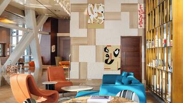 A modern lobby with a geometric wall design, seating areas, and a bookshelf.