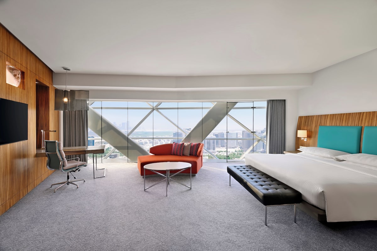Ein modernes Hotelzimmer mit einem großen Bett, einer Couch, einem kleinen Tisch und einem Schreibtisch mit Stuhl.
