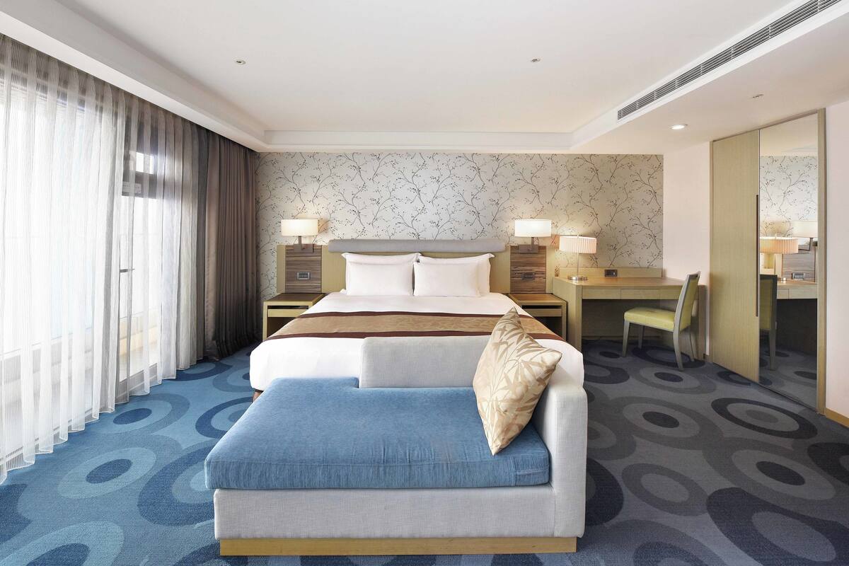 Een hotelkamer met een bed, een slaapbank, een bureau en een stoel.