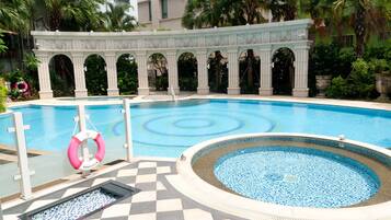 Relax by the pool surrounded by lush greenery and a decorative mosaic design.