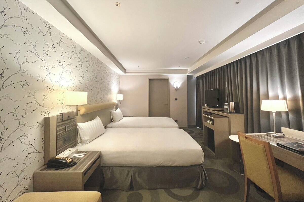 Een hotelkamer met een groot bed, nachtkastjes, een bureau, een stoel, een televisie en een kledingkast.