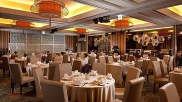 A banquet hall with round tables, chairs, and decorative lighting fixtures.
