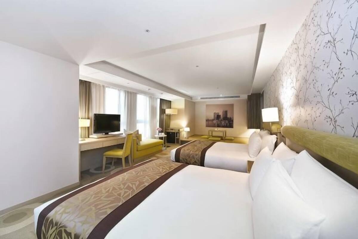 Een hotelkamer met een groot bed, een bureau met stoel, een televisie en uitzicht op de stad.