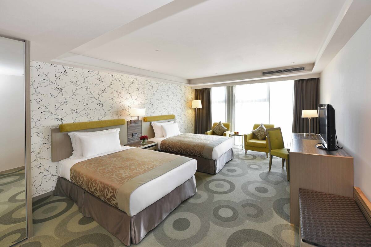 Een hotelkamer met twee bedden, een bureau, een stoel en een televisie.