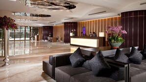 Eine moderne Hotelhalle mit Empfangsschalter, Sitzgelegenheiten und einer großen Pflanze in einem Topf.