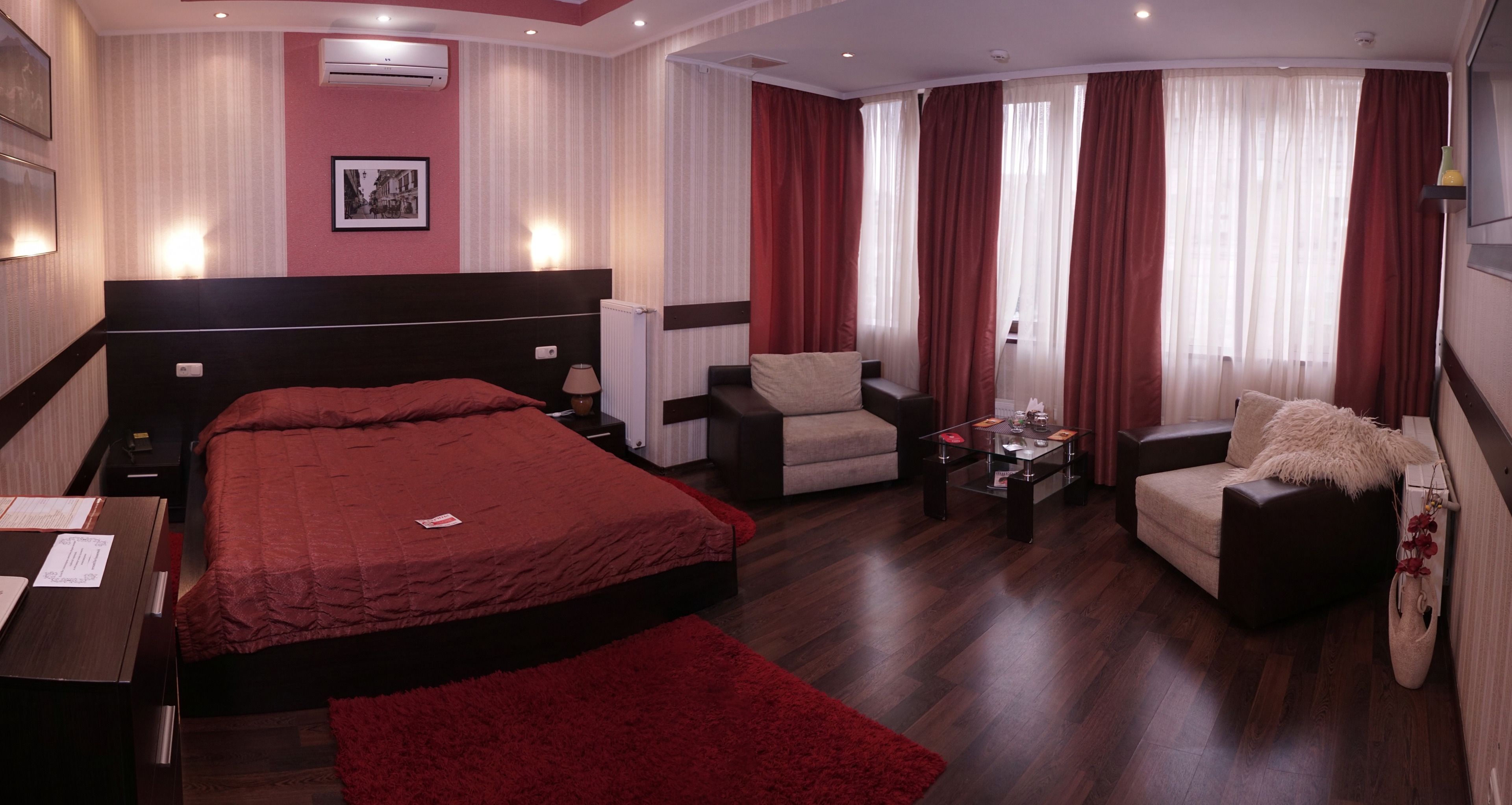 Une chambre d’hôtel avec un grand lit, deux fauteuils, une petite table et un canapé.