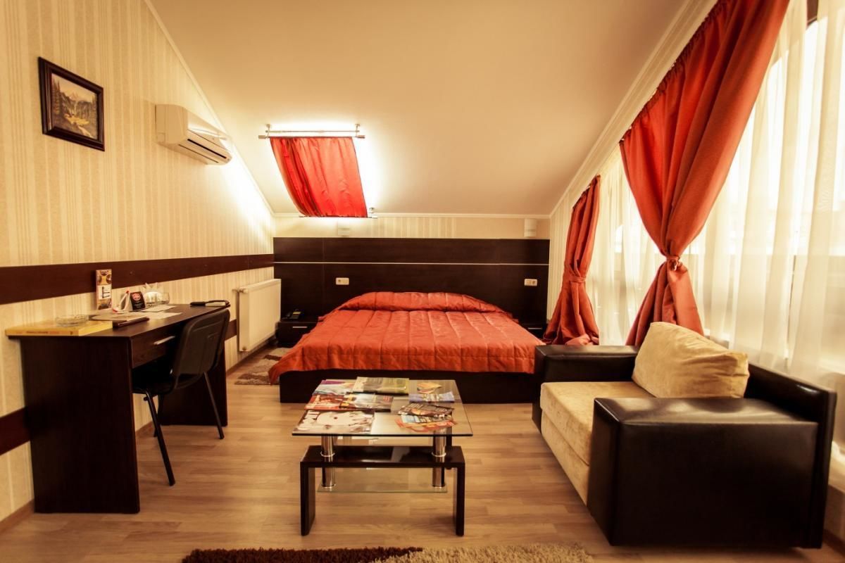 A compact bedroom with a bed, a desk, a sofa, and a coffee table.