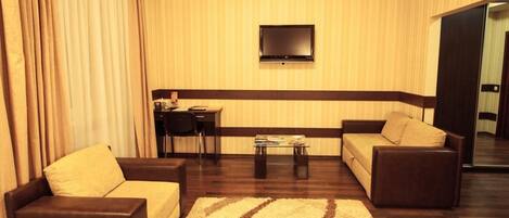 Una sala de estar con dos sofás, una mesa de centro y un televisor montado en la pared.