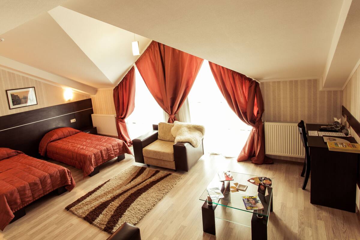 Una habitación de hotel con dos camas, un sofá, una mesa de centro de vidrio y un escritorio con una silla.