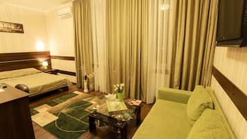 A hotel room with a bed, a sofa, a desk, and a TV.