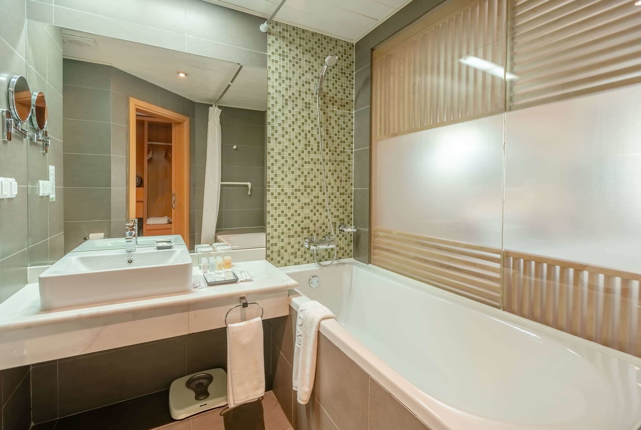 A modern bathroom with a large bathtub, a vanity with a mirror, and a shower area.